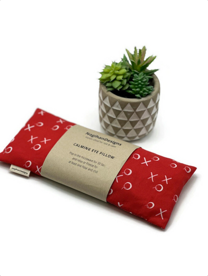 red fabric eye pillow with x's and o's